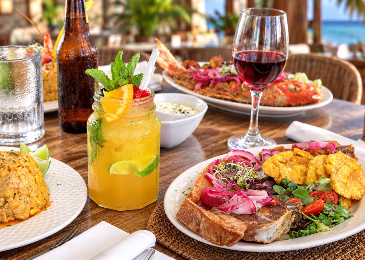 Mesa servida con mofongo, pescado y bebidas frente al mar